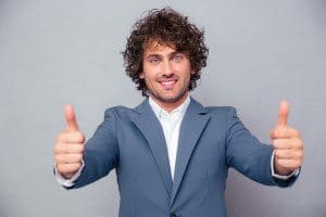 Smiling businessman standing with thumbs up